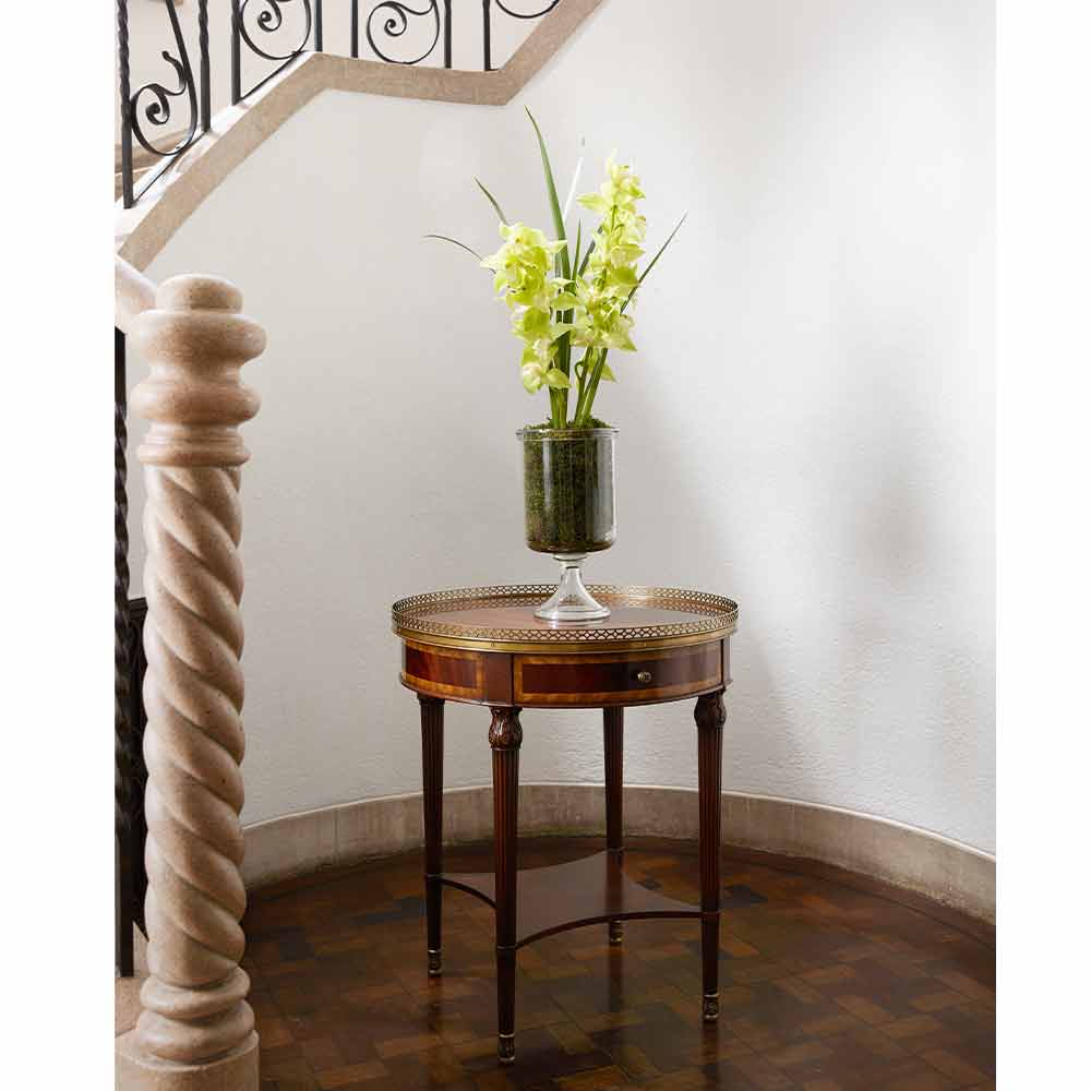 螺旋階段の踊り場に置かれているイメージ画像　クラシックテイスト　サイドテーブルの上には黄色の花が挿してある透明の花瓶が置かれている
